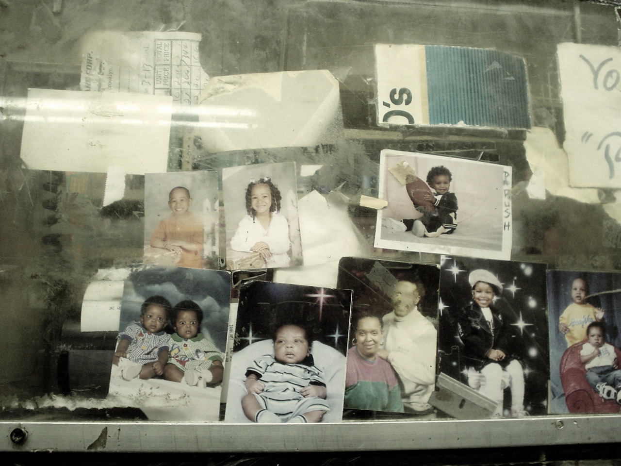NEIGHBORHOOD KIDS PHOTOS TAPED TO THE BULLET PROOF GLASS OF THE BODEGA
